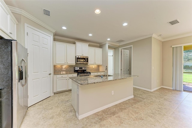 kitchen with sink, appliances with stainless steel finishes, white cabinetry, light stone countertops, and an island with sink