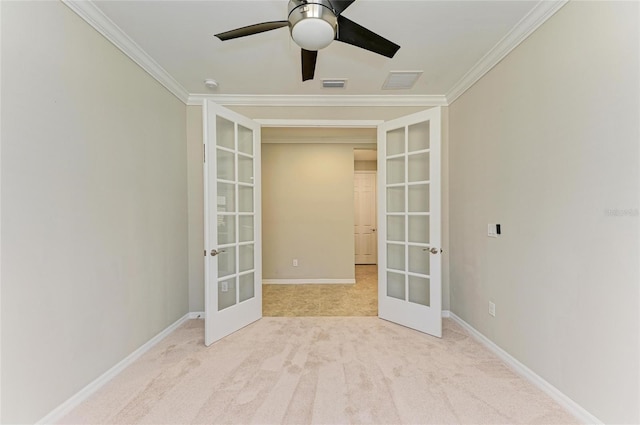 carpeted spare room with crown molding, ceiling fan, and french doors