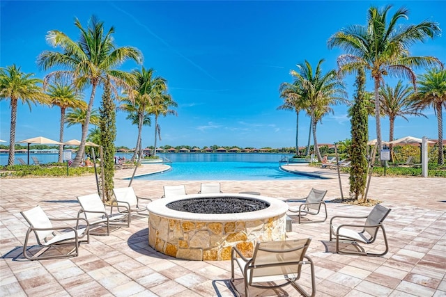 view of swimming pool with a fire pit, a patio, and a water view