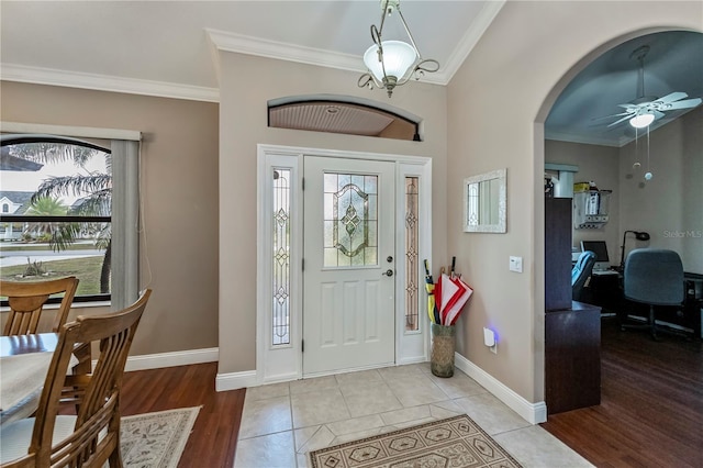 tiled foyer entrance featuring crown molding and ceiling fan