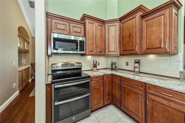 kitchen with decorative backsplash, light stone countertops, and appliances with stainless steel finishes