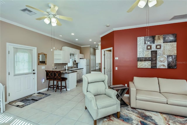 tiled living room with ornamental molding, sink, and ceiling fan