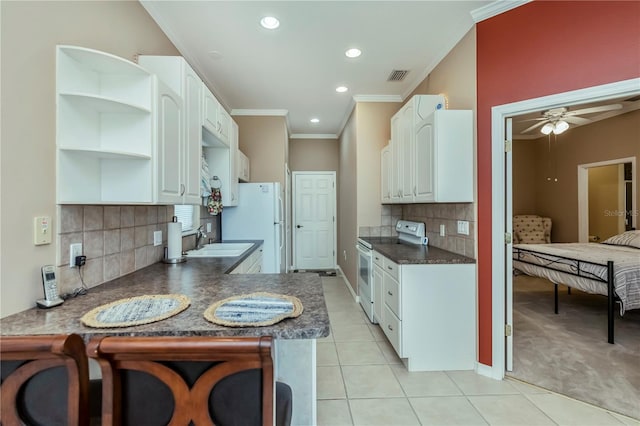 kitchen with white cabinets, light tile patterned floors, kitchen peninsula, crown molding, and white appliances