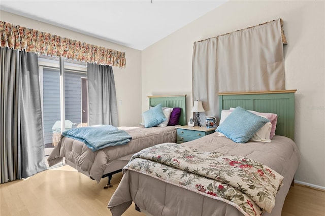 bedroom with hardwood / wood-style flooring, lofted ceiling, and access to exterior