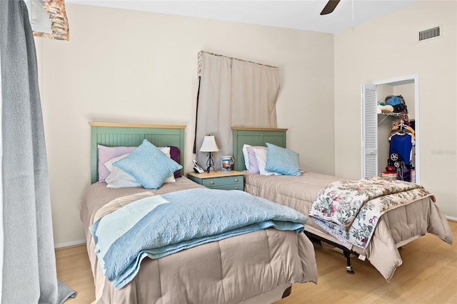 bedroom featuring ceiling fan, a walk in closet, light wood-type flooring, and a closet