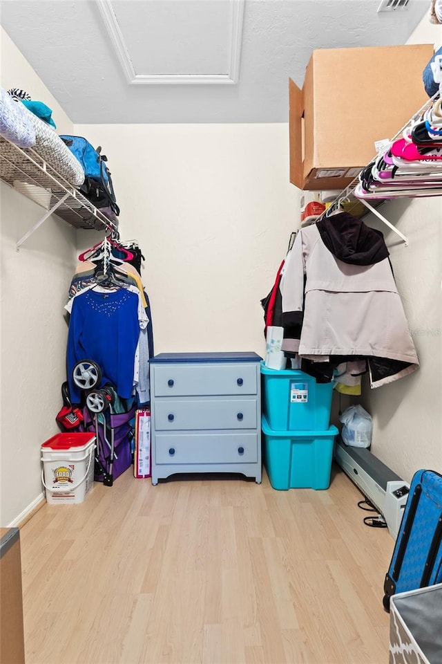 walk in closet with light hardwood / wood-style flooring