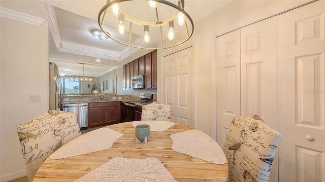 dining room with ornamental molding, a raised ceiling, sink, and light wood-type flooring