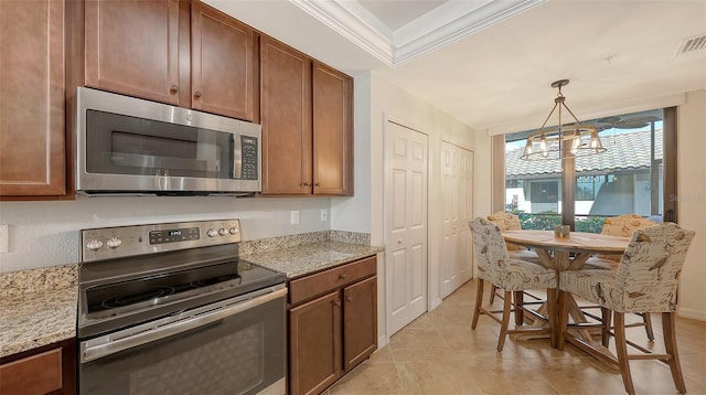 kitchen with light stone counters, ornamental molding, appliances with stainless steel finishes, and decorative light fixtures