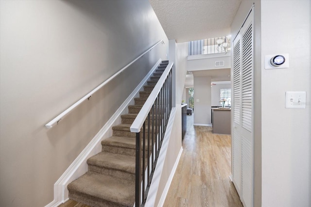 stairs with hardwood / wood-style flooring and a textured ceiling