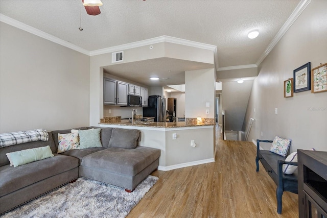 living room with sink, ceiling fan, light hardwood / wood-style floors, crown molding, and a textured ceiling