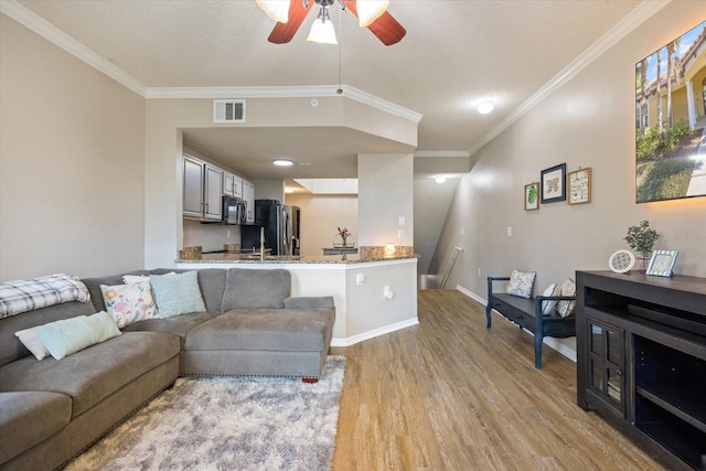 living room with crown molding, ceiling fan, a textured ceiling, and light hardwood / wood-style floors