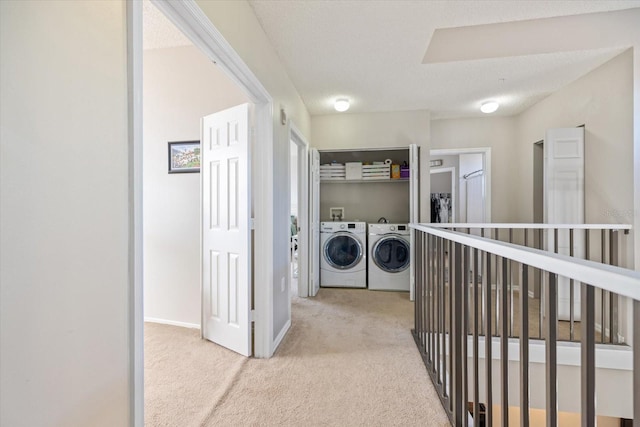 laundry area featuring washer and clothes dryer, light carpet, and a textured ceiling