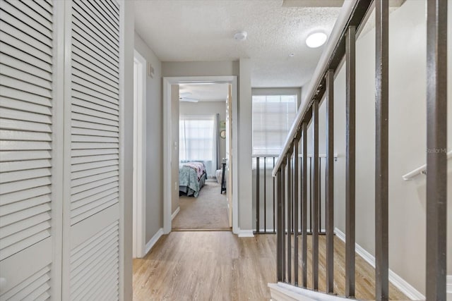 corridor featuring light hardwood / wood-style floors and a textured ceiling