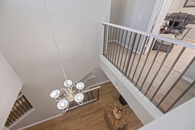 stairs with wood-type flooring and a chandelier