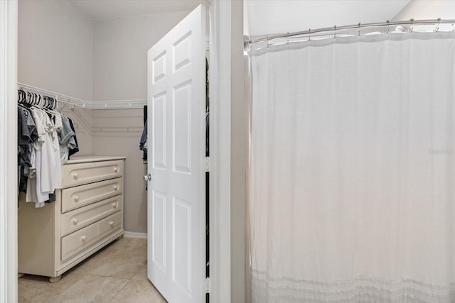 walk in closet with light tile patterned floors