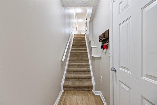 staircase featuring hardwood / wood-style floors and a textured ceiling