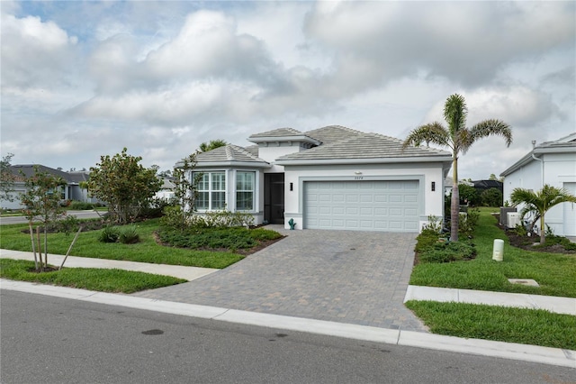 view of front of house featuring a garage, central AC, decorative driveway, and a front yard