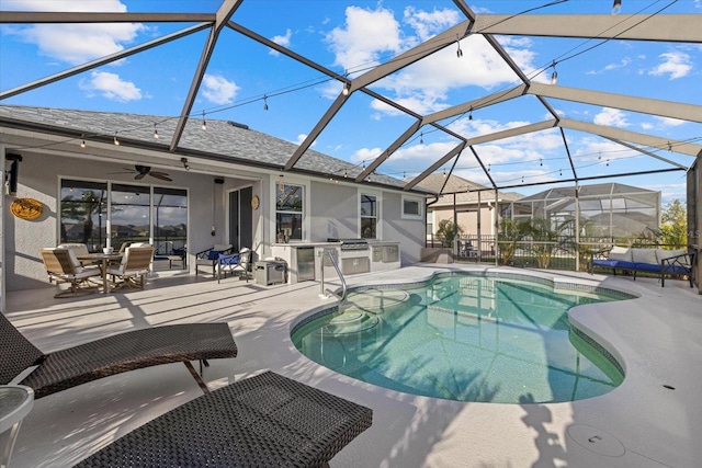 view of pool with a lanai, a patio area, ceiling fan, and exterior kitchen