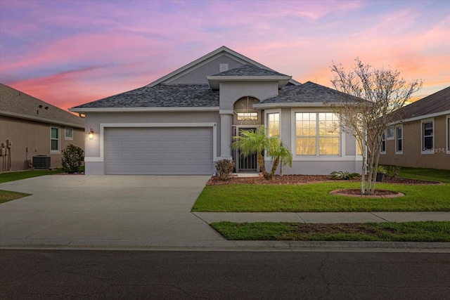 view of front of house with a garage, a yard, and central AC unit