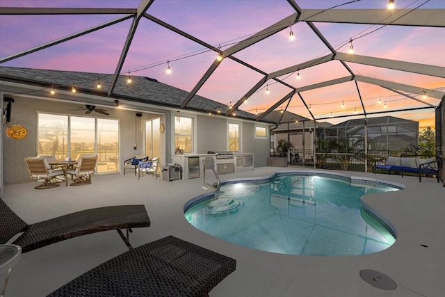 pool at dusk featuring ceiling fan, area for grilling, a patio area, and glass enclosure