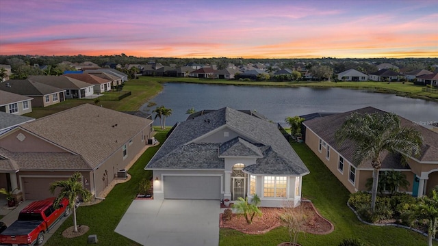 aerial view at dusk featuring a water view