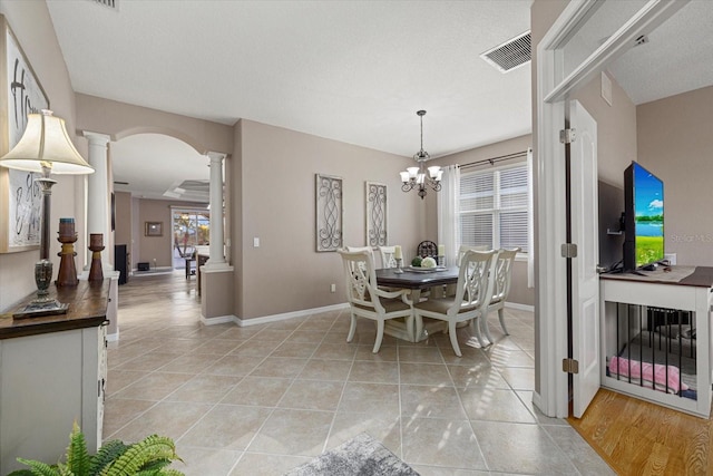 dining room with a chandelier, decorative columns, and light tile patterned floors