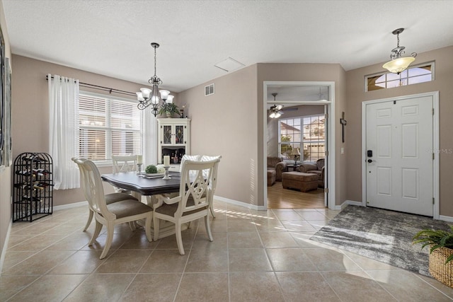 tiled dining space with a wealth of natural light, a textured ceiling, and a chandelier