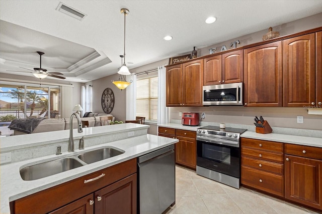 kitchen featuring sink, decorative light fixtures, light tile patterned floors, appliances with stainless steel finishes, and a raised ceiling