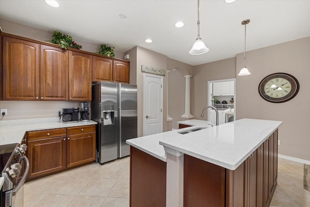 kitchen with sink, appliances with stainless steel finishes, a kitchen island with sink, washing machine and dryer, and ornate columns