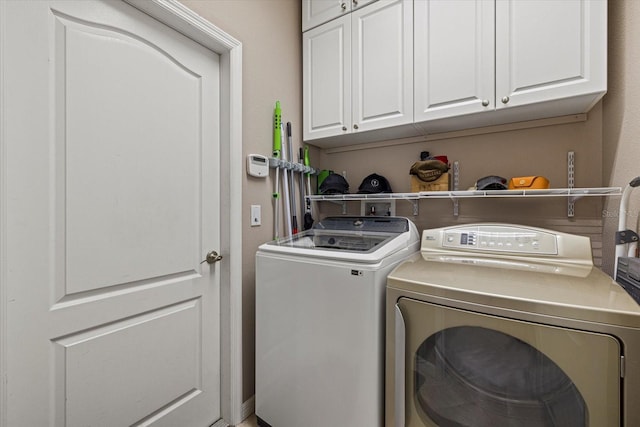 clothes washing area featuring cabinets and washing machine and clothes dryer