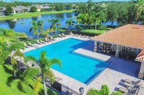 view of pool featuring a water view and a patio