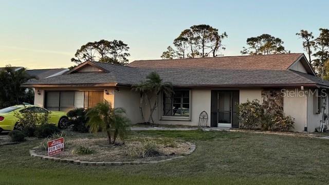 ranch-style house featuring a garage, a yard, and stucco siding