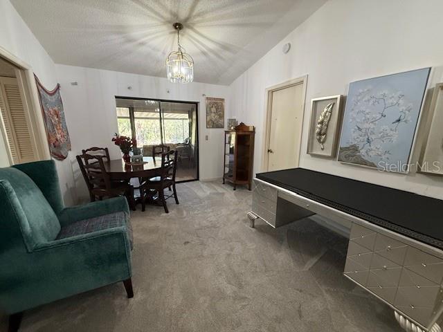 interior space with light carpet, lofted ceiling, and an inviting chandelier