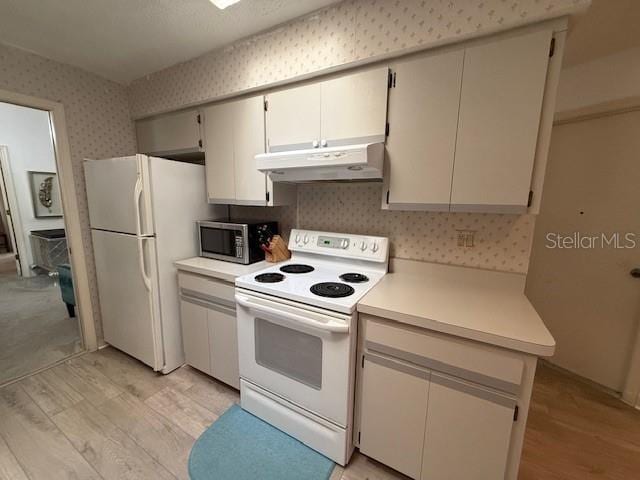 kitchen with wallpapered walls, white appliances, light wood-style floors, light countertops, and under cabinet range hood