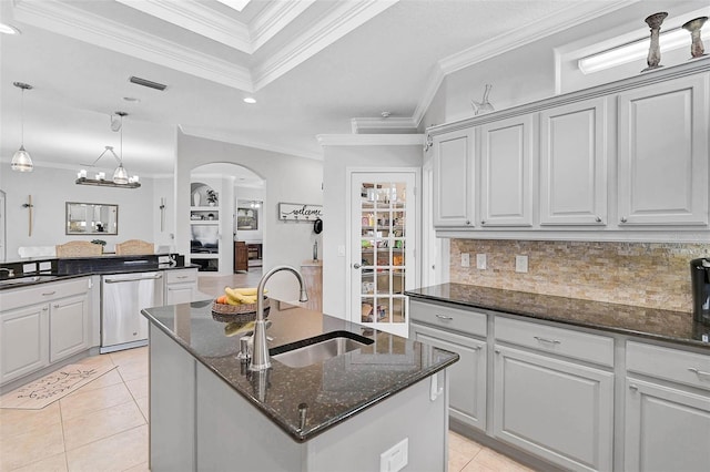 kitchen featuring sink, dishwasher, dark stone countertops, an island with sink, and light tile patterned flooring