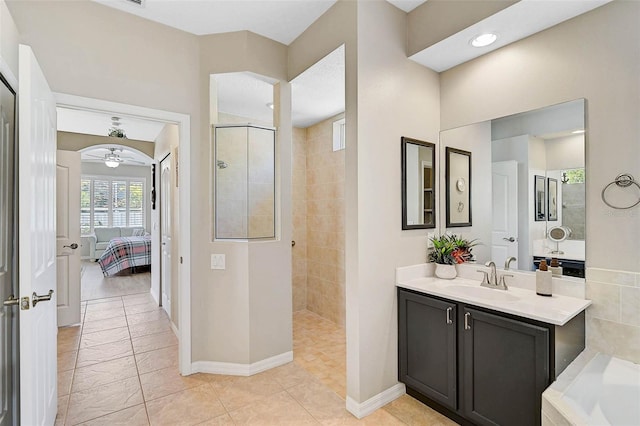 bathroom with tile patterned flooring, vanity, tiled shower, and ceiling fan