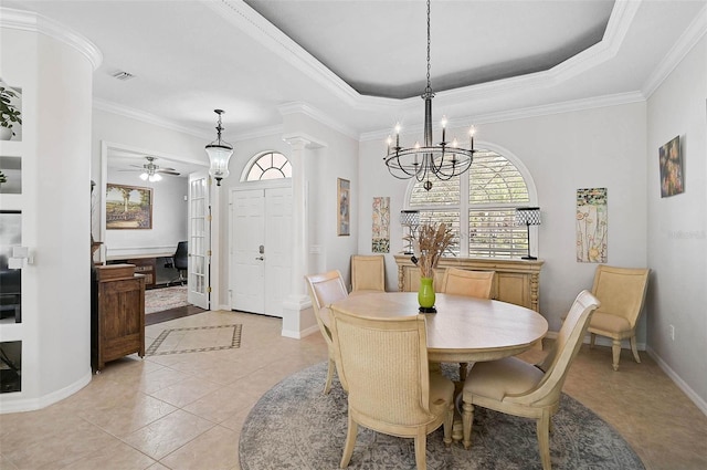 tiled dining area featuring a raised ceiling, crown molding, ceiling fan with notable chandelier, and decorative columns