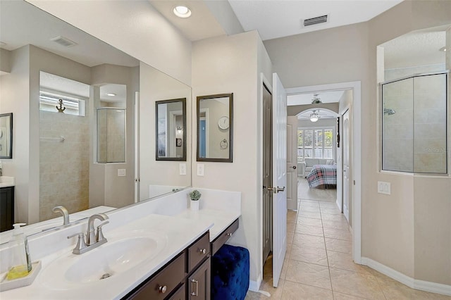 bathroom with ceiling fan, vanity, a shower with shower door, and tile patterned flooring