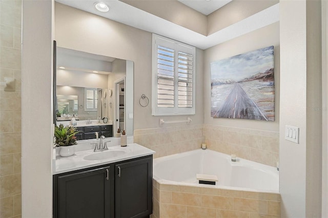 bathroom with vanity and tiled tub