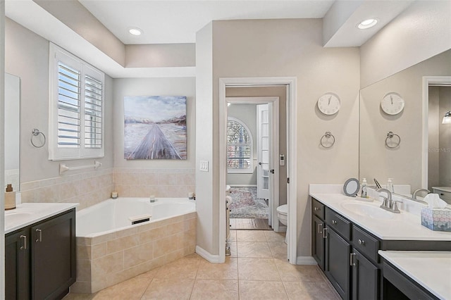 bathroom featuring vanity, tile patterned floors, tiled bath, and toilet