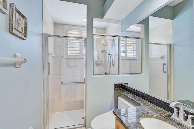 bathroom with vanity, a shower with shower door, and toilet