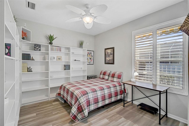 bedroom featuring ceiling fan, hardwood / wood-style floors, and multiple windows