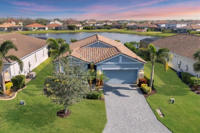 aerial view at dusk featuring a residential view and a water view