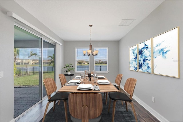 dining room featuring a chandelier, dark wood finished floors, visible vents, and baseboards