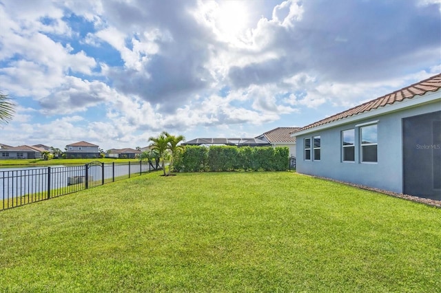 view of yard featuring a residential view, a fenced backyard, and a water view