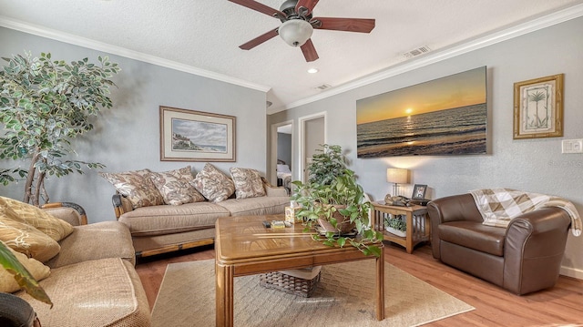 living room featuring crown molding, ceiling fan, a textured ceiling, and light hardwood / wood-style floors