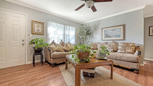 living room featuring ornamental molding, ceiling fan, a textured ceiling, and light hardwood / wood-style floors