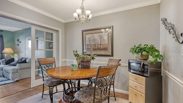 dining space featuring ornamental molding, an inviting chandelier, and light hardwood / wood-style flooring