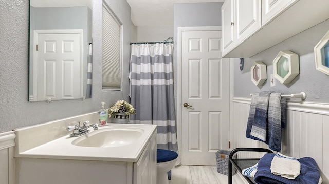 bathroom with hardwood / wood-style flooring, vanity, a shower with curtain, and toilet