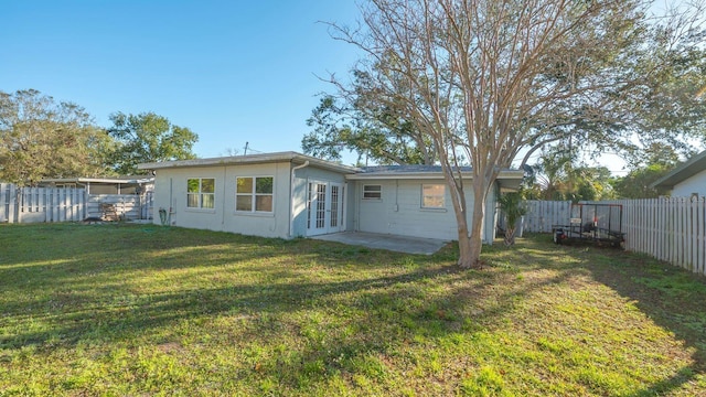 back of property with a yard, a patio area, and french doors